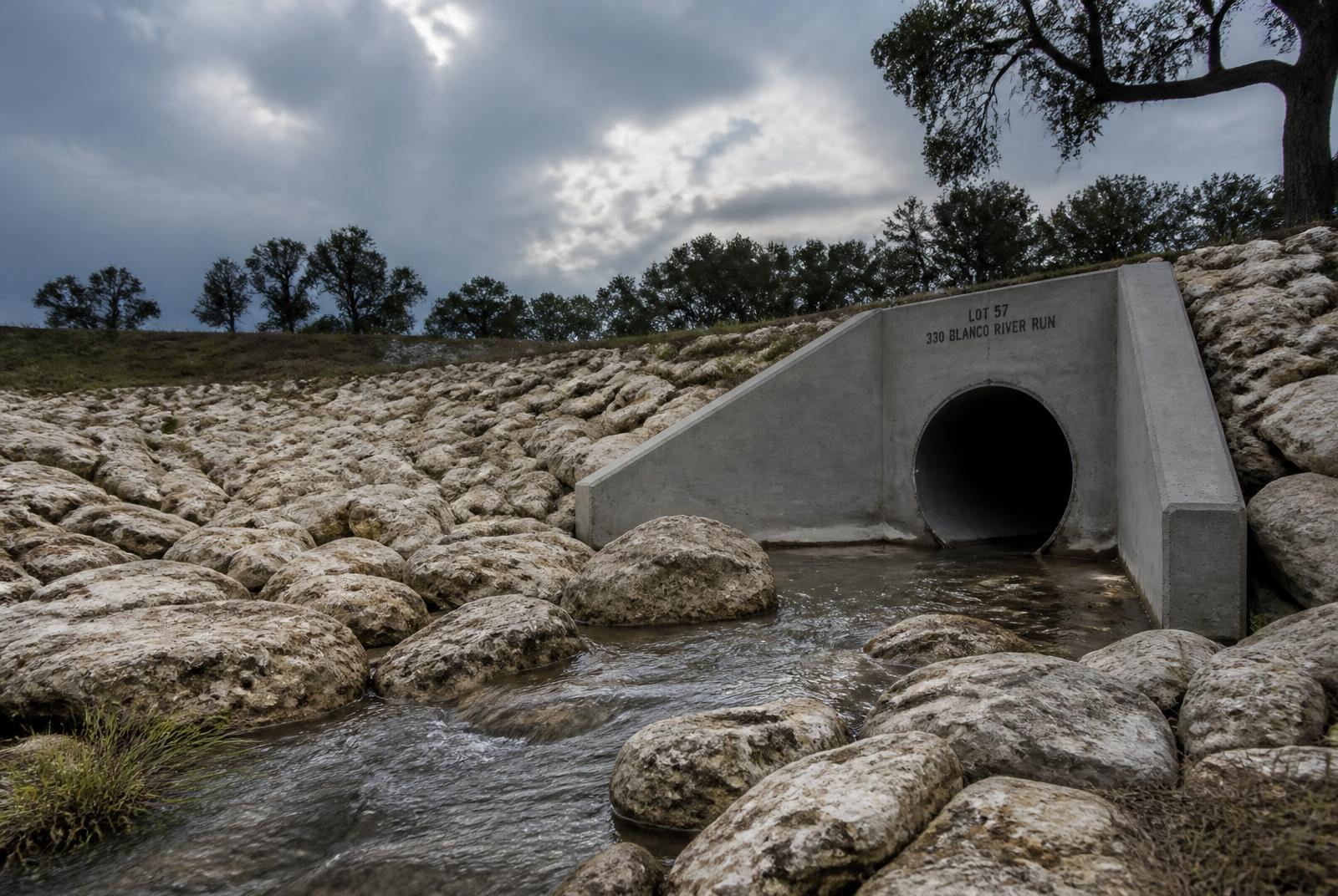 Riprap-lined drainage swale with a concrete culvert wing wall